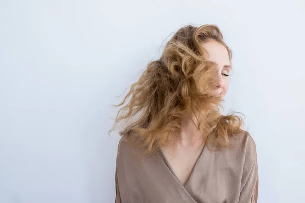 Retrato de uma jovem menina bonita que acena o cabelo em um fundo branco . — Fotografia de Stock