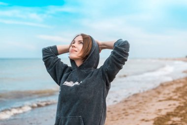 Ceketli, denizde oturan bir kadın, okyanus. Doğa konseptinde dinlence, rahatlama.