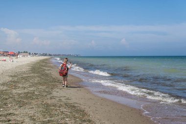 Küçük çocuk fotoğrafçı. Sırt çantası olan bir çocuk plajda fotoğraf yapar.