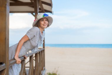 Verandada oturan mutlu orta yaşlı kadın, sahilde çardak, okyanus.