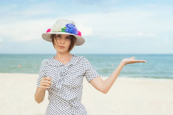 Žena středního věku v klobouku a oblékat se na břeh, oceán drží dlaň vzhůru. Místo pro text. Volný čas, dovolená, mír, koncept svobody. — Stock fotografie