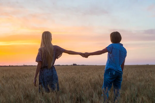Mom of middle age and daughter teenager in a field at sunset. Relationship, understanding between parent and child.
