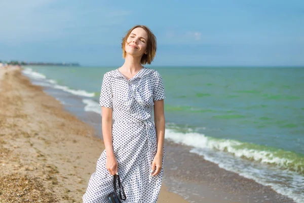 En kvinna i en klänning går längs stranden. Frihet, semesterkoncept. — Stockfoto