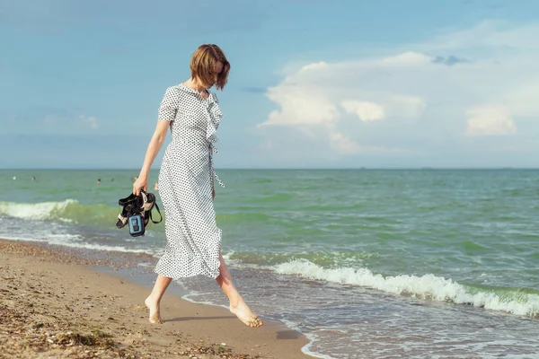 A woman in a dress walks along the seashore. Freedom, vacation concept. — Stock Photo, Image