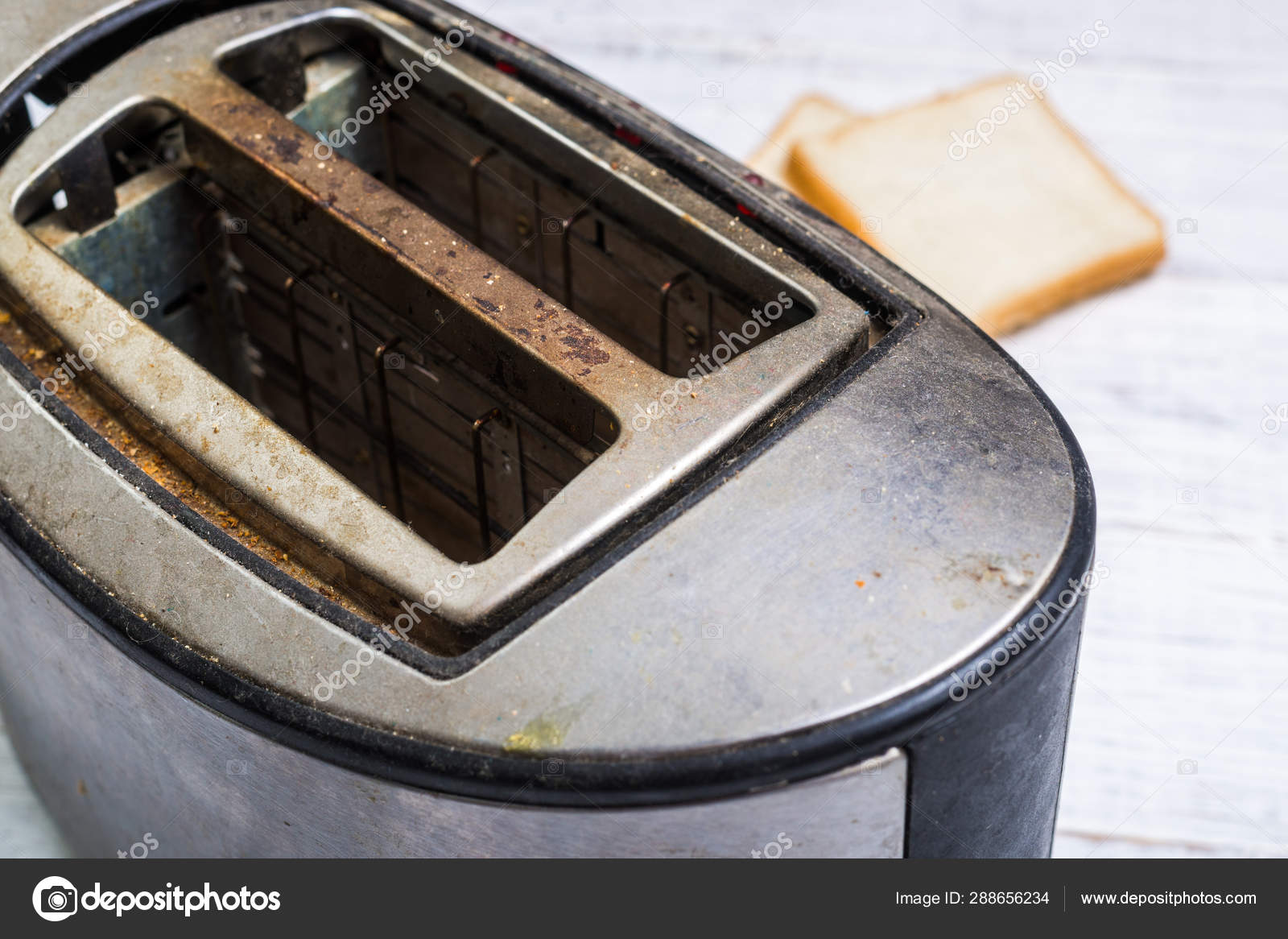 Dirty old toaster with bread on a white wooden background. Stock Photo