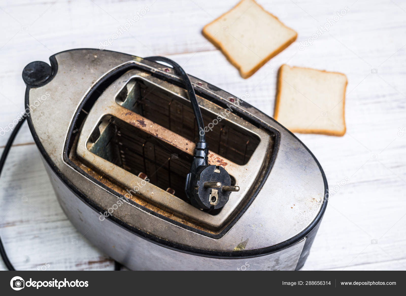 Dirty old toaster with bread on a white wooden background. Stock Photo