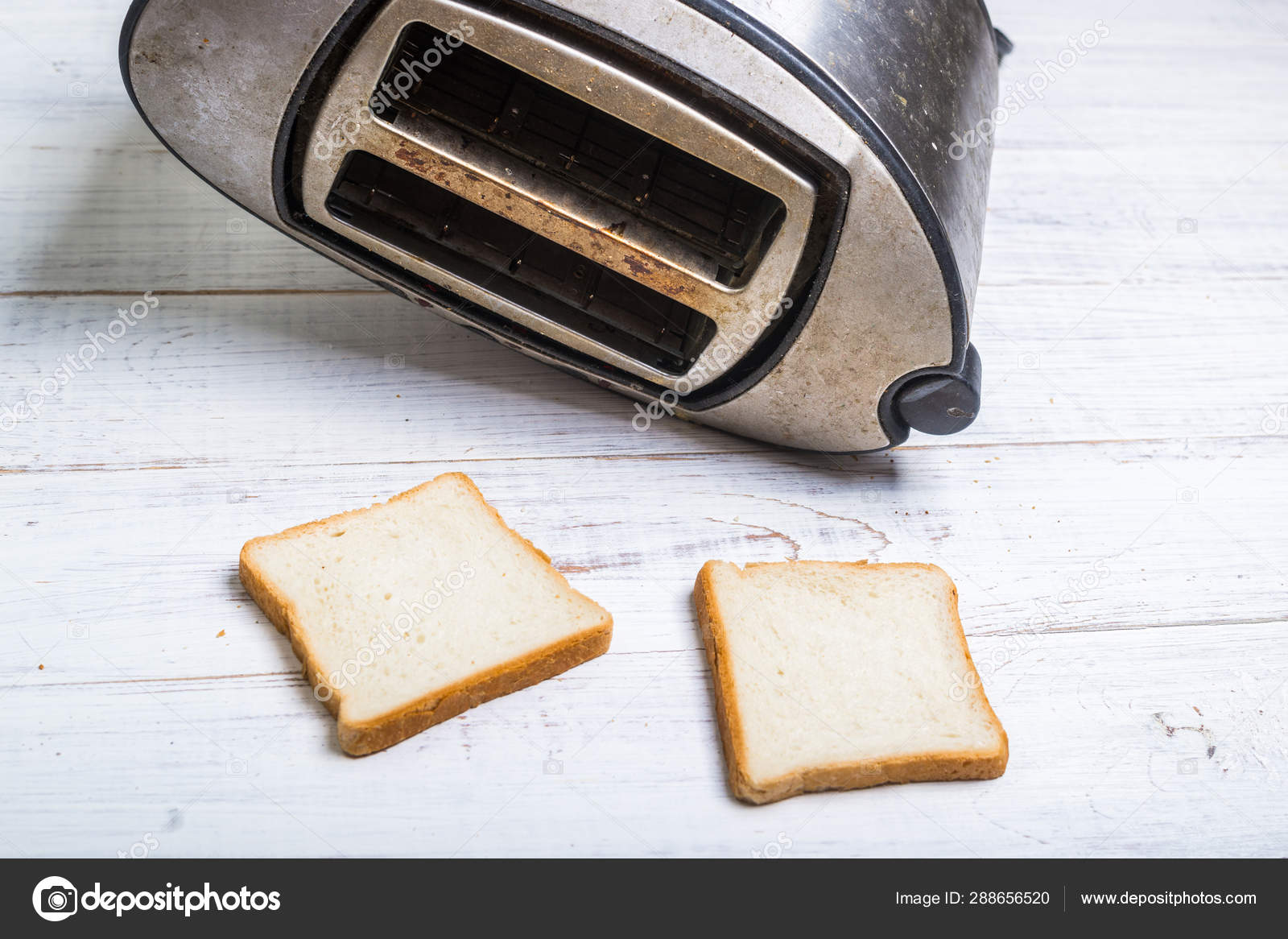 Dirty old toaster with bread on a white wooden background. Stock Photo