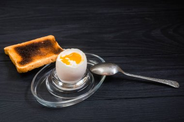 Siyah ahşap arka planda haşlanmış yumuşak haşlanmış tavuk yumurtası.