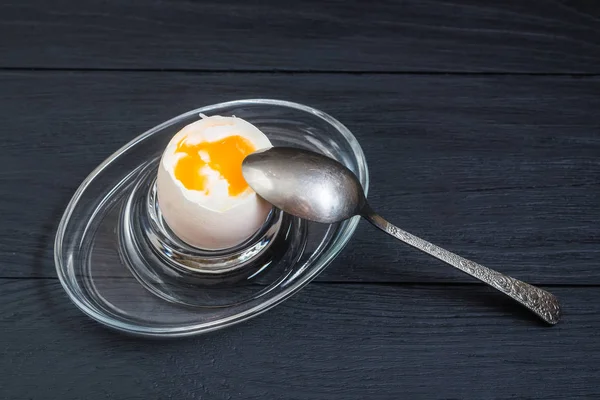 Boiled soft-boiled chicken egg on a black wooden background.