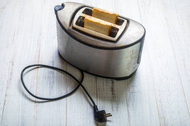 Beyaz ahşap arka planda ekmek ile kirli eski tost makinesi.