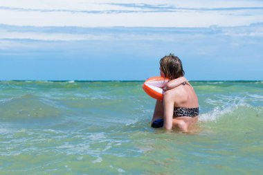 Küçük oğlu olan anne deniz dalgalarında yüzen. Bir kadın ve küçük bir çocuk suya sıçrayan.