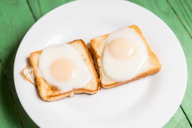 Beyaz bir tabak üzerinde kızarmış yumurta ile tost. Tavuk yumurtası ile sandviç. Snack, Kahvaltı.