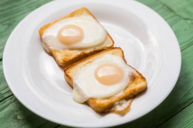 Beyaz bir tabak üzerinde kızarmış yumurta ile tost. Tavuk yumurtası ile sandviç. Snack, Kahvaltı.