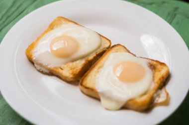 Beyaz bir tabak üzerinde kızarmış yumurta ile tost. Tavuk yumurtası ile sandviç. Snack, Kahvaltı.