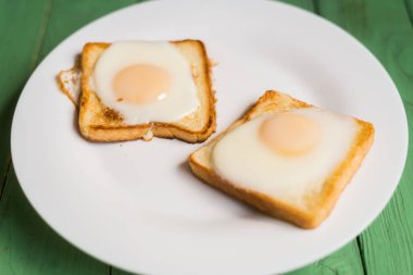 Beyaz bir tabak üzerinde kızarmış yumurta ile tost. Tavuk yumurtası ile sandviç. Snack, Kahvaltı.