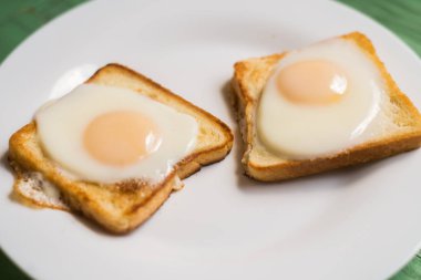 Beyaz bir tabak üzerinde kızarmış yumurta ile tost. Tavuk yumurtası ile sandviç. Snack, Kahvaltı.