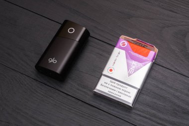 Kiev, Ukrayna-Temmuz 28, 2019: GLO-tütün Isıtma ve siyah ahşap arka planda sigara için ambalaj çubukları için bir cihaz.