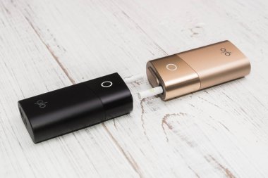 Kiev, Ukrayna-28 Temmuz 2019: GLO-Beyaz ahşap arka planda tütün ve sigara ısıtmak için iki cihaz.