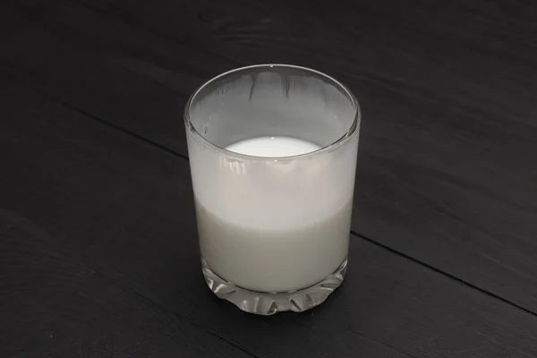 Verre à moitié vide avec kéfir, yaourt, lait sur fond de bois noir . — Photo