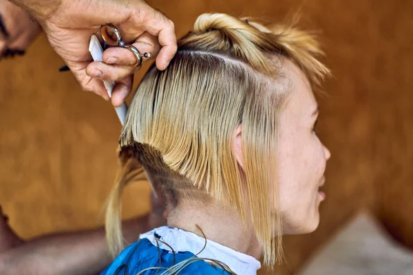 Blonde woman at the hairdresser. Hair master makes a fashionable haircut. — Stock Photo, Image