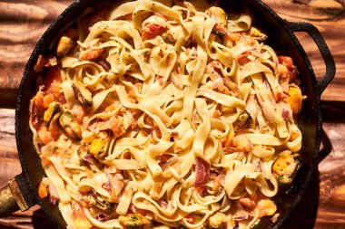 Spagetti, midye, domates, soğan ve tavada krema sos ile makarna.