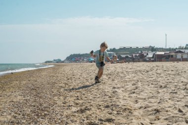 Bir kamera ile küçük bir çocuk sahil boyunca çalışır.