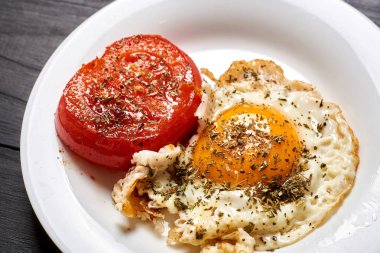 Ahşap bir zeminde ızgara yumurta ve ızgara domates. Hızlı ve kolay hazırlanan kahvaltı..