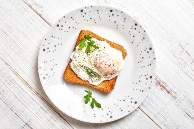 Haşlanmış yumurta, kızarmış ekmek üzerine Benedict salata ve ahşap bir tabakta baharat..