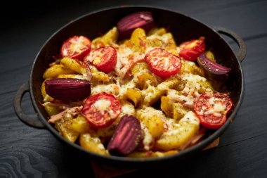 Pişmiş patates, fırında domates, pastırma ve peynirli tavada.
