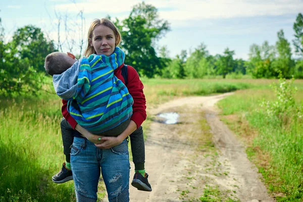 Annem yeşil bir parkta kucağında bir bebek taşıyor..