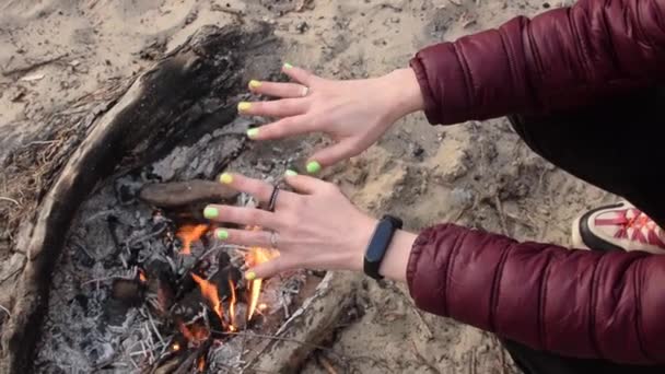 女性は手を火の近くで暖める — ストック動画