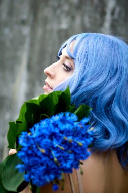 Sokakta elinde bir buket mavi çiçekle dolaşan kız..