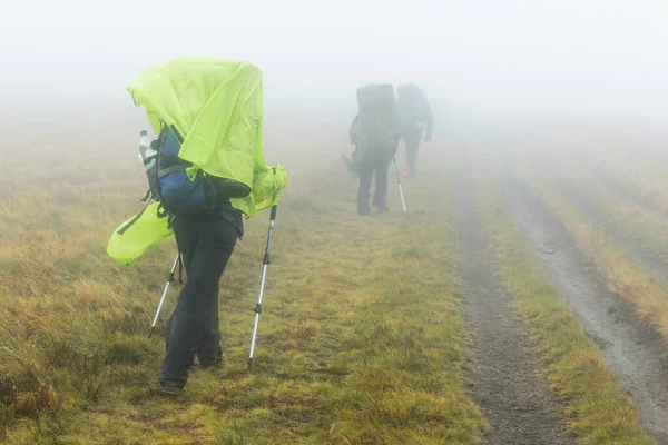 Woman with backpack hiking in the fog.