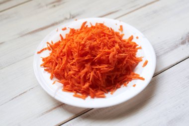 Hafif ahşap arka planda, tabakta rendelenmiş havuçlar..