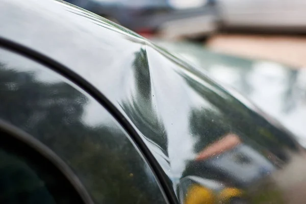 A small dent in the coating of a black car