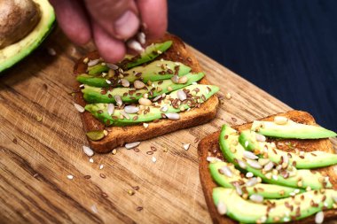 Dilimlenmiş avokadoyla tost, ahşap arka planda tohumların karışımı. Yarın sağlıklı atıştırmalıklar var. Düzgün beslenme, diyet kavramı.