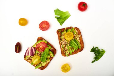 Sebzeli tost, avokado, domates, beyaz arka planda bir dizi tohum. Sağlıklı yemek, diyet konsepti.