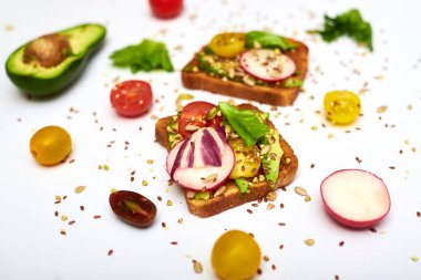 Sebzeli tost, avokado, domates, beyaz arka planda bir dizi tohum. Sağlıklı yemek, diyet konsepti.