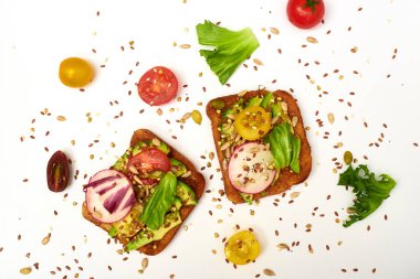 Sebzeli tost, avokado, domates, beyaz arka planda bir dizi tohum. Sağlıklı yemek, diyet konsepti.