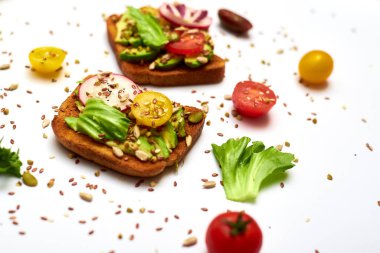 Sebzeli tost, avokado, domates, beyaz arka planda bir dizi tohum. Sağlıklı yemek, diyet konsepti.