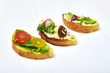 Krem peynirli ciabatta, avokado, çeşitli sebzeler. Beyaz arka planda vejetaryen sandviçler..