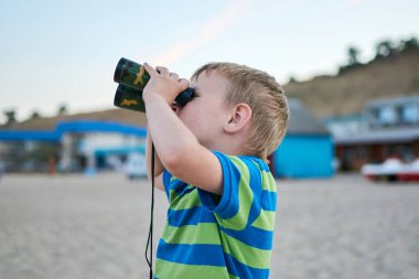 Yazın kumsalda elinde dürbünü olan bir çocuk..