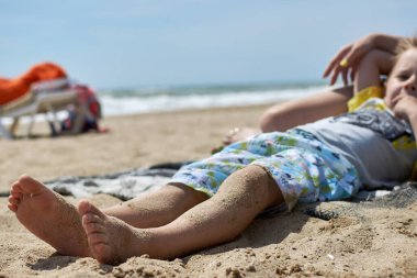 Kumsaldaki kumda bir çocuğun ayakları. Dikkatsizlik ve rahatlama kavramı..