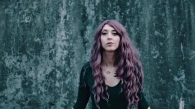 Çekici bir kız uzun saçlarını koyu beton bir arka plana doğru sallıyor..