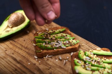 Dilimlenmiş avokadoyla tost, ahşap arka planda tohumların karışımı. Yarın sağlıklı atıştırmalıklar var. Düzgün beslenme, diyet kavramı.
