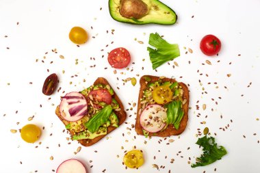 Sebzeli tost, avokado, domates, beyaz arka planda bir dizi tohum. Sağlıklı yemek, diyet konsepti.