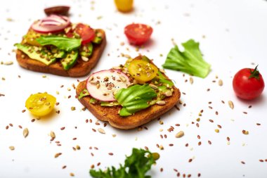 Sebzeli tost, avokado, domates, beyaz arka planda bir dizi tohum. Sağlıklı yemek, diyet konsepti.