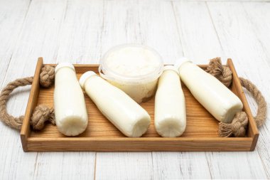 Süt ürünleri şişeleri ve ahşap tepside bir kavanoz süzme peynir. Organik, sağlıklı yiyecekler..