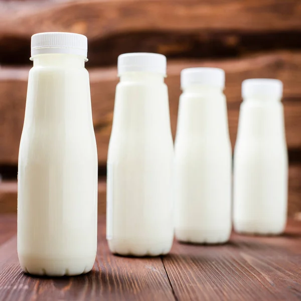 Bottles with milk, yogurt on a wooden background. Natural dairy products.