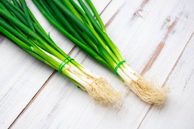 Hafif ahşap zemin üzerinde bir demet yeşil soğan.